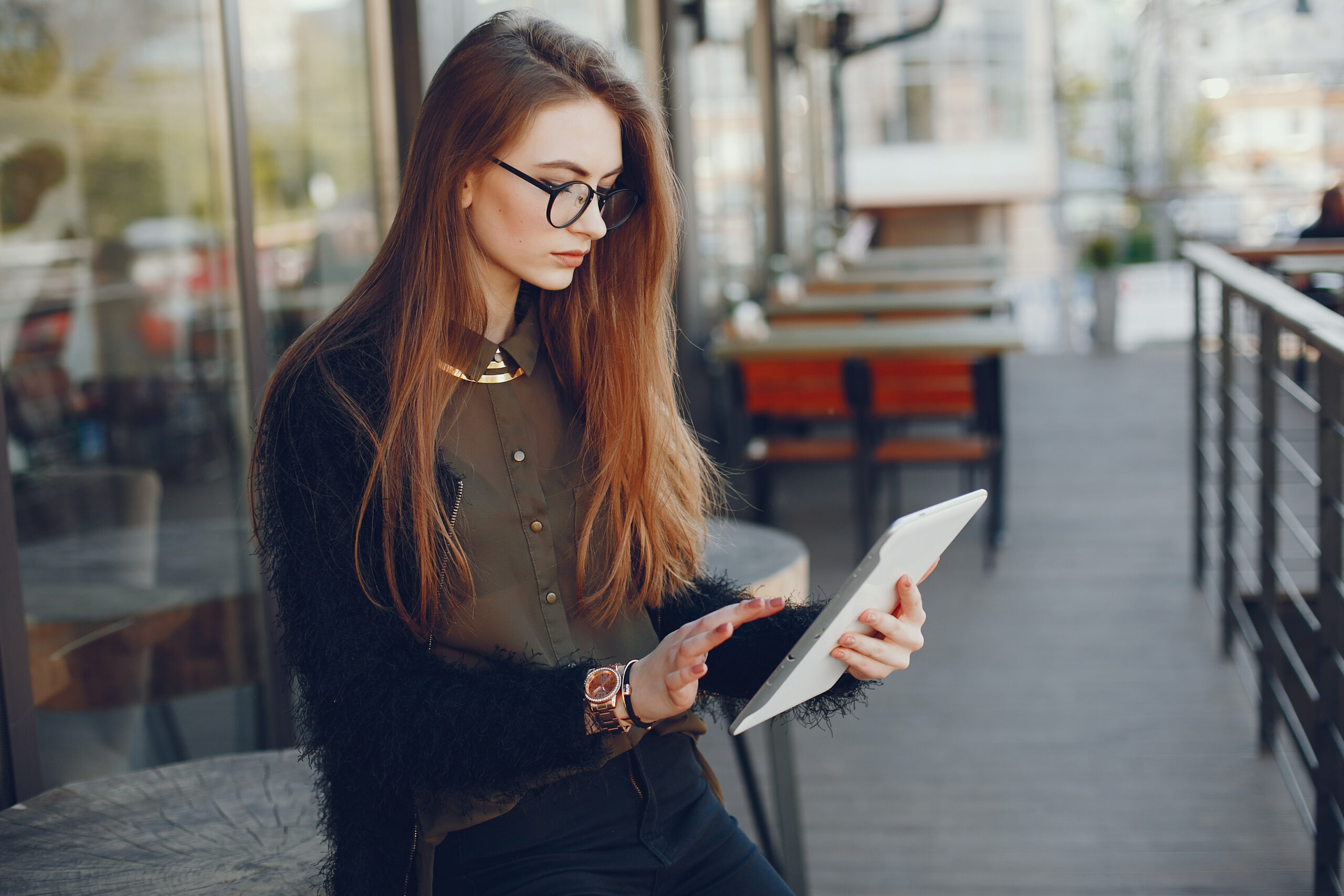 Stylish woman sitting in a restaurant. Businesswoman working at the cafe. Girl use the tablet. Lady in a glasses